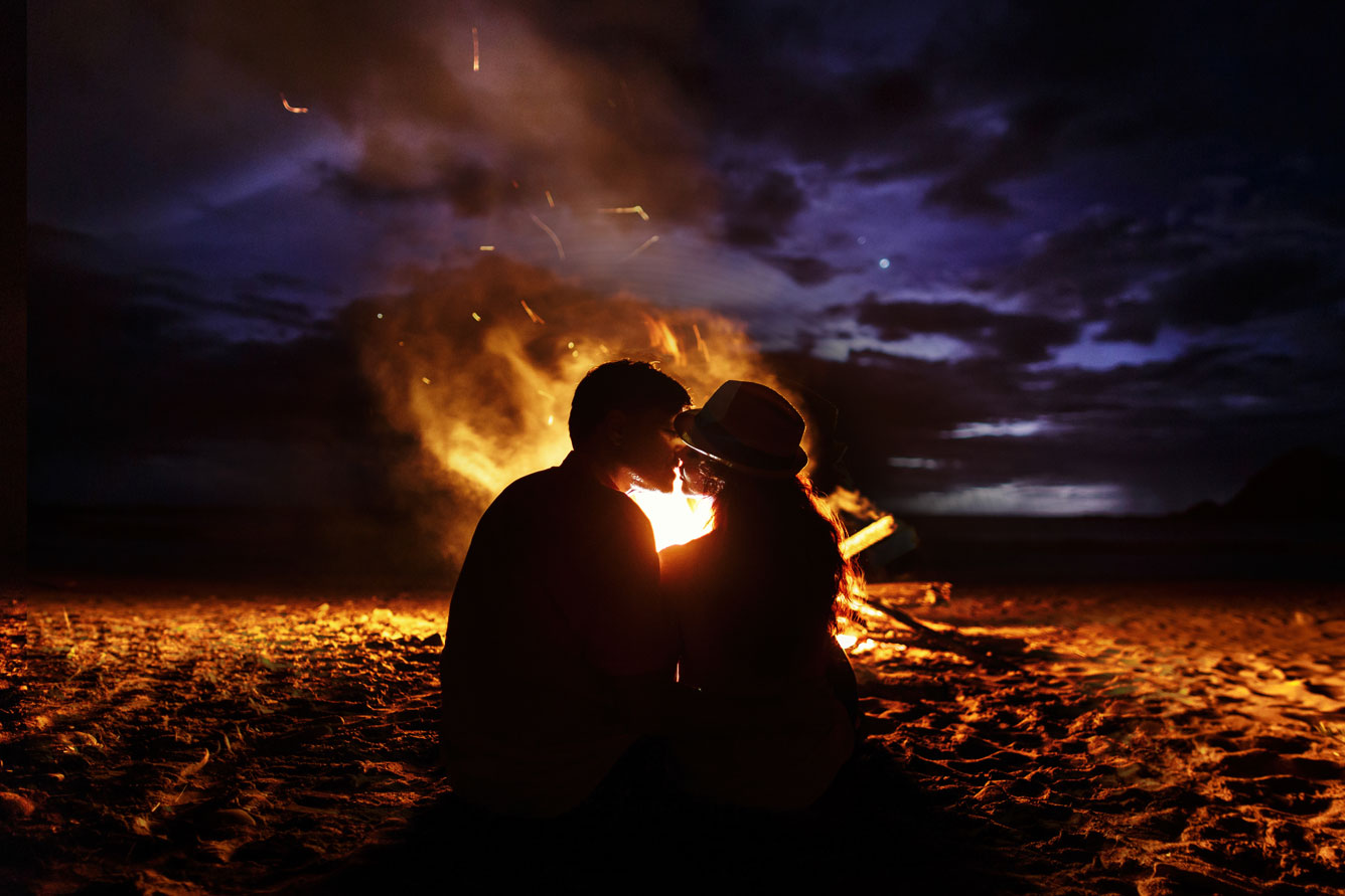 pareja-besos-sienta-chimenea-playa